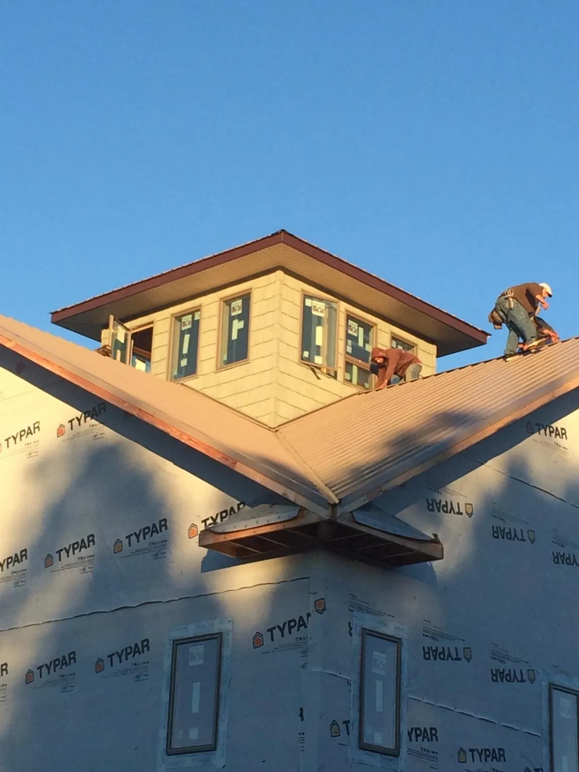 Roofers working around a rooftop cupola on a new metal roof at sunset — Roof Waterproofing in Denton by Roofing Brothers